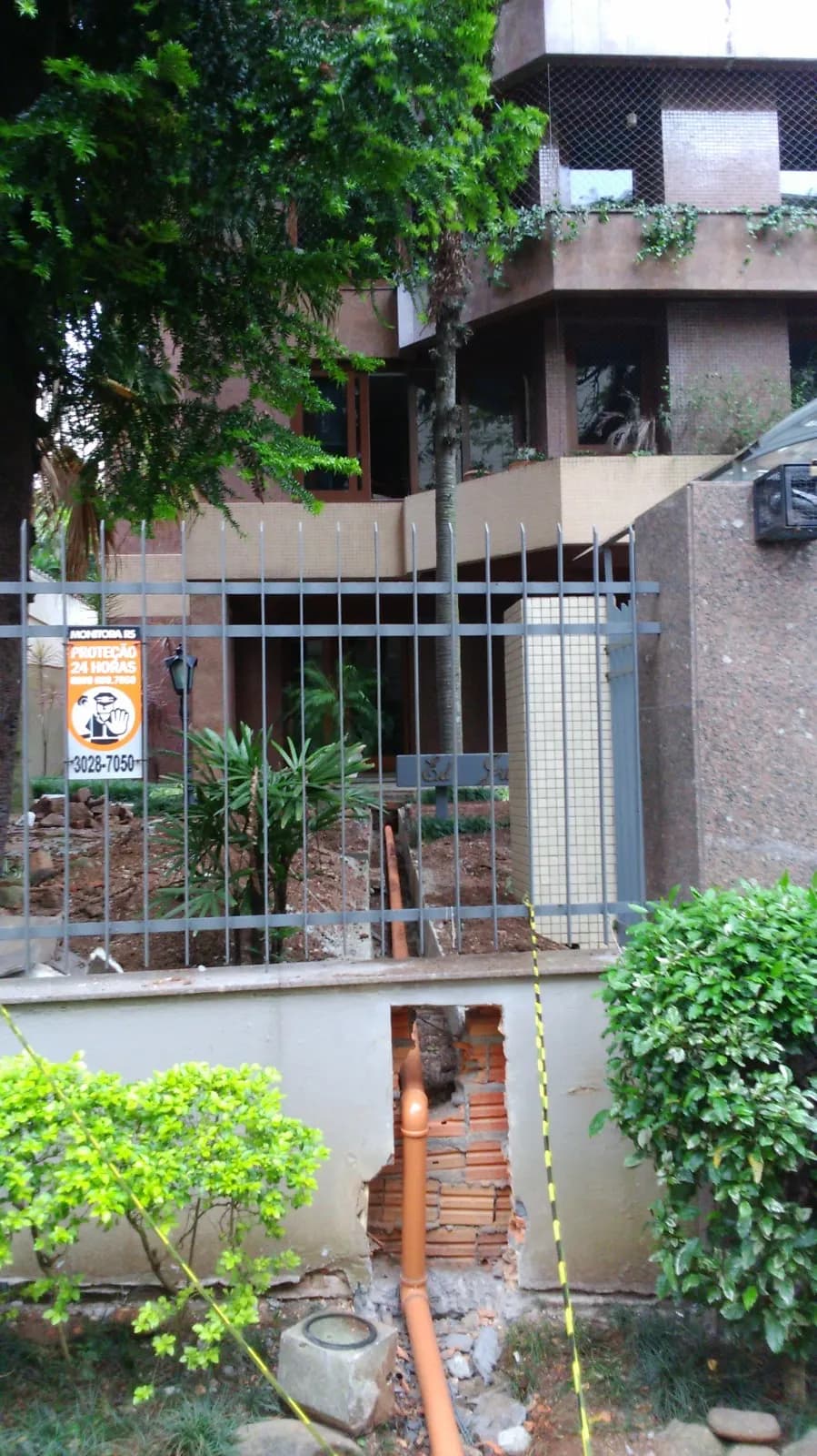 Escavação para rede de esgoto junto ao muro de condomínio